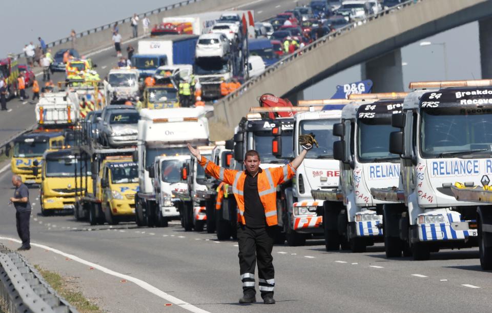 A rescue worker gestures in front of recovery trucks lined up to collect over 100 vehicles involved in multiple collisions, which took place in dense fog during the morning rush hour, on the Sheppey Bridge in Kent, east of London