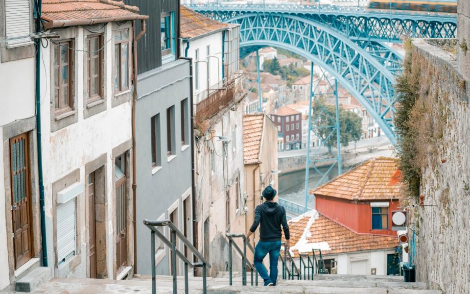 Tourist in the old town of Porto looking at Dom Luis I bridge - Marco Bottigelli/Getty
