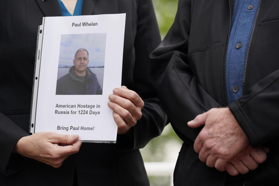 Elizabeth Whelan, left, sister of U.S. Marine Corps veteran and Russian prisoner Paul Whelan, holds a photo of her brother as she stands alongside Joey Reed, father of U.S. Marine Corps veteran and recently released Russian prisoner Trevor Reed, before a news conference with families of Americans currently being held hostage or wrongfully detained overseas in Lafayette Park near the White House, Wednesday, May 4, 2022, in Washington. (AP Photo/Patrick Semansky)