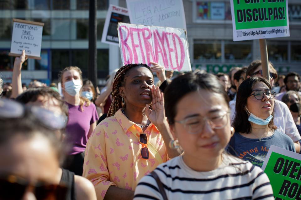 "Betrayed" in pink letters appears on a poster held up at a protest.