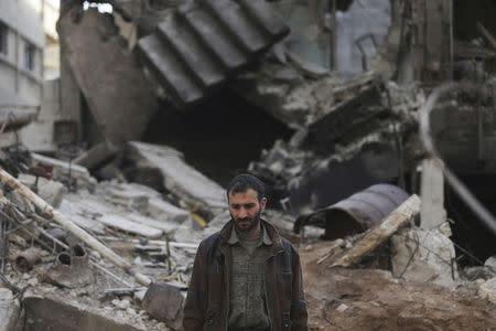 A man, whose relatives are trapped under the rubble of his house, reacts at a site hit by what activists said were airstrikes by forces loyal to Syria's President Bashar al-Assad in the Douma neighborhood of Damascus, February 9, 2015. REUTERS/ Bassam Khabieh