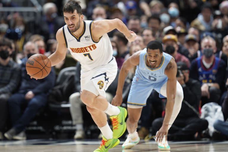 Denver Nuggets guard Facundo Campazzo, front, picks up a loose ball in front of Memphis Grizzlies guard De'Anthony Melton during the first half of an NBA basketball game Friday, Jan. 21, 2022, in Denver. (AP Photo/David Zalubowski)