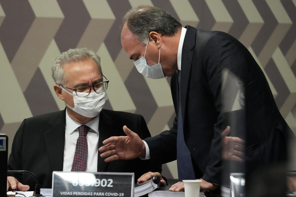 Senators Renan Calheiros, left, and Fernando Bezerra talk during the reading of a Senate commission report on the government's handling of the COVID-19 pandemic at the Federal Senate in Brasilia, Brazil, Wednesday, Oct. 20, 2021. A senator formally presented a report recommending President Jair Bolsonaro be indicted on criminal charges for allegedly bungling Brazil's response to the pandemic and pushing the country's death toll to second-highest in the world. (AP Photo/Eraldo Peres)