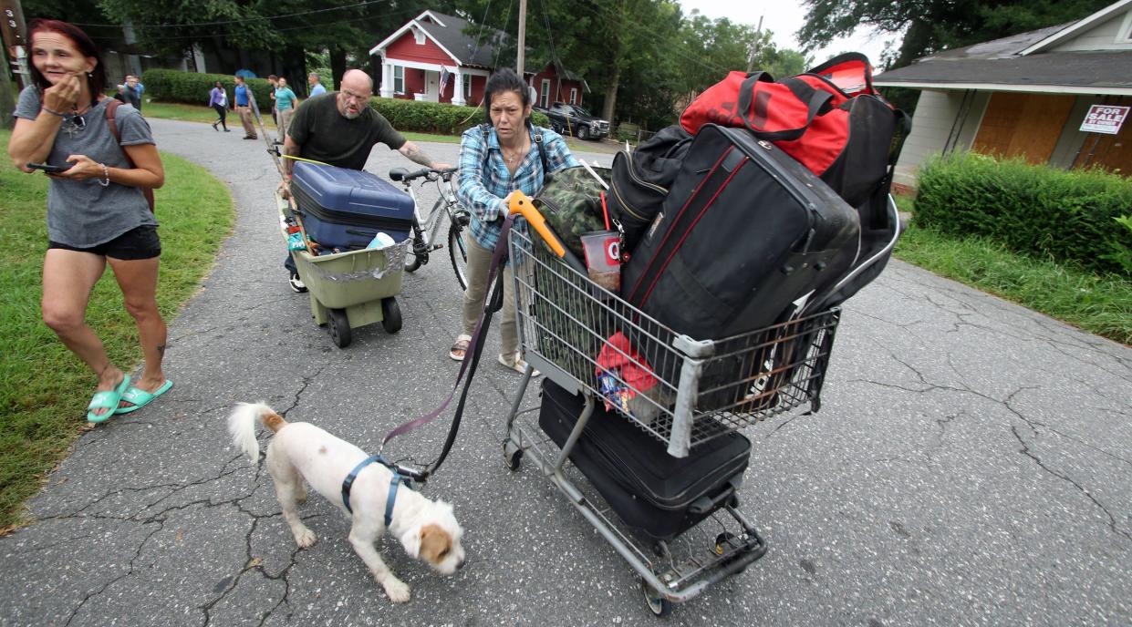 Wayne Moore and Amanda Vannoy, along with their dog Masters, push their belongings along North Oakland Street as they and others vacate the homeless encampment behind Faith, Hope and Love Community Enrichment Ministries early Monday morning.