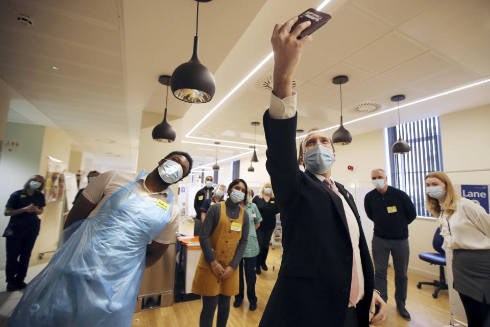 FILE - In this Wednesday, Feb. 17, 2021 file photo, Britain's Health Secretary Matt Hancock takes a selfie with the vaccine hub staff during a visit to the Queen Elizabeth Hospital in Birmingham, England, to thank volunteers undertaking clinical trials for the COVID-19 vaccinations. The British government says it aims to give every adult in the country a first dose of coronavirus vaccine by July 31, a month earlier than its previous target. In addition, the goal is for everyone over 50 or with an underlying health condition to get a shot by April 15, rather than the previous target of May 1. (Molly Darlington/Pool via AP, File)