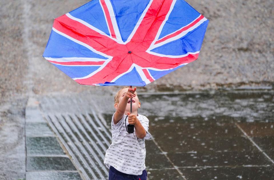 A young boy battles with an umbrella on the South Bank (PA)