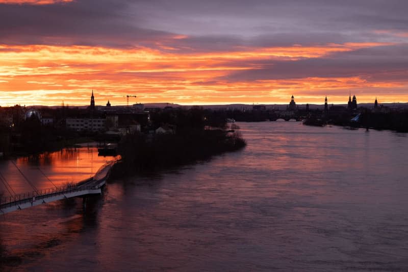 The Elbe floods against the backdrop of the old town at sunrise. The flood situation in Saxony remains tense, especially on the Elbe. Sebastian Kahnert/dpa