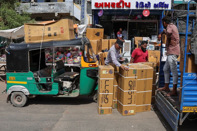 Workers count boxes of air conditioners outside a shop during the heat wave in Ahmedabad