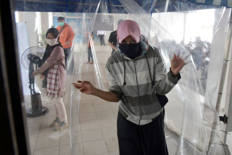 Woman wearing a face mask leaves a disinfection chamber amid the spread of coronavirus disease (COVID-19) outbreak in Pekanbaru