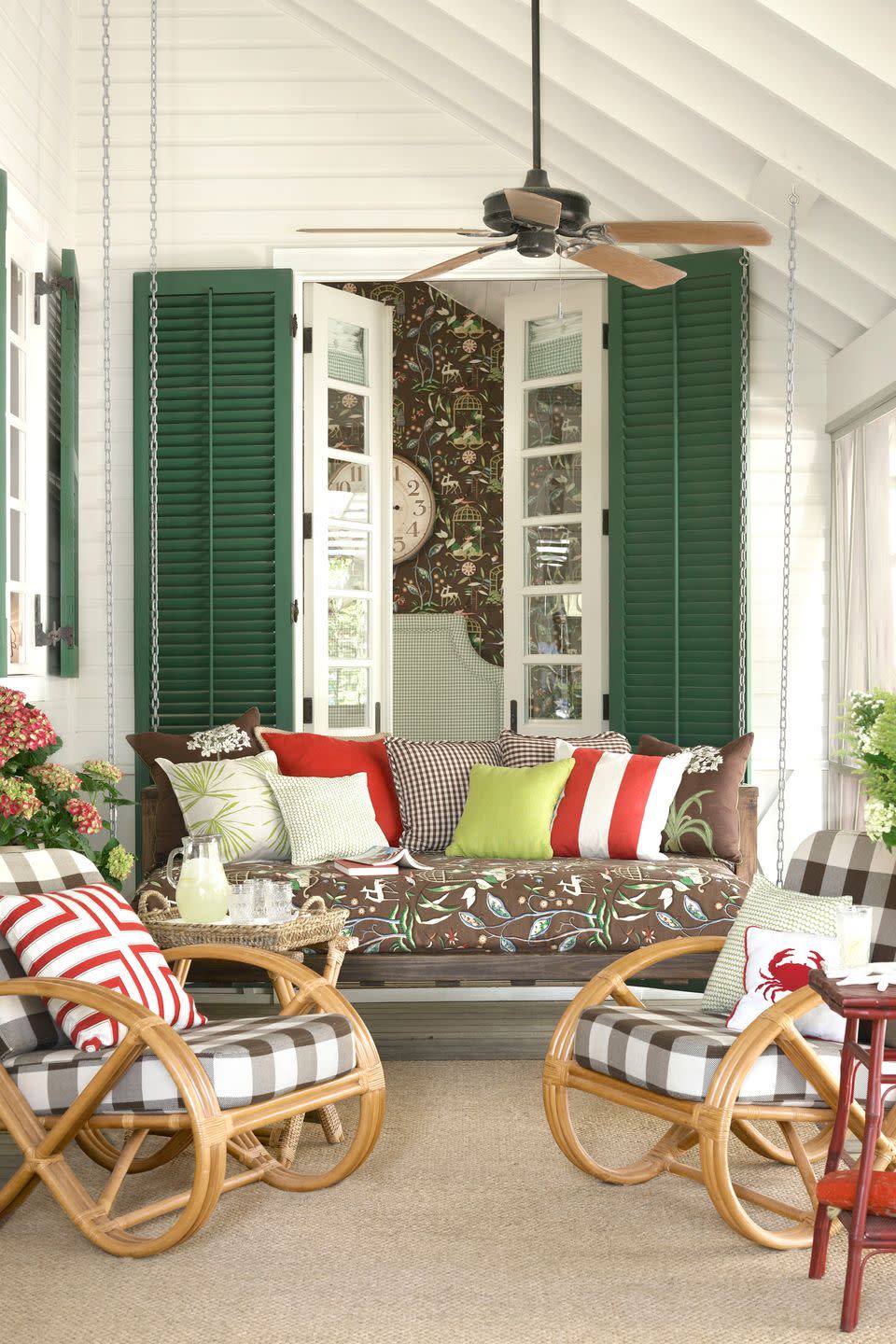 colorful screened in porch with green shutters and rattan chairs