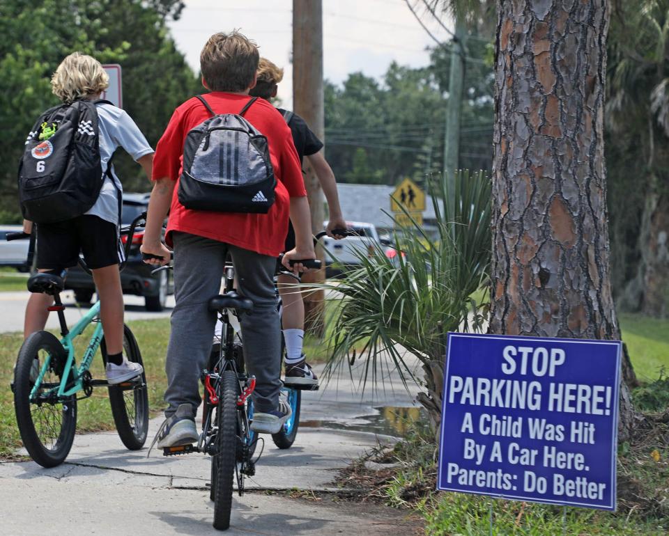 Kids on bikes ride by a sign that warns of a previous accident and urges parents to improve safety as Sugar Mill Elementary lets out Tuesday, May 28, 2024.