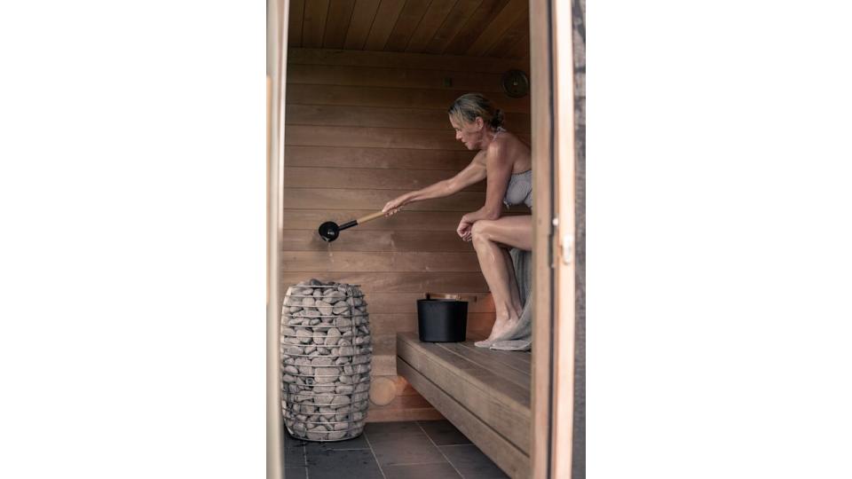 Woman pouring water in a sauna