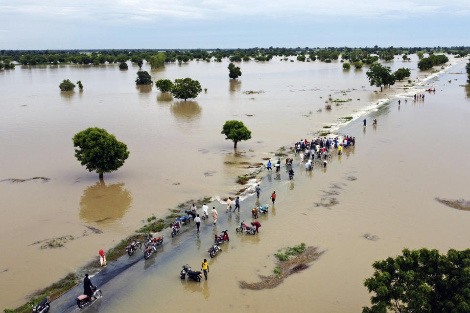 La gente camina en medio de una zona inundada el 19 de septiembre de 2022, luego de lluvias intensas, en Hadeja, Nigeria. El país africano enfrenta sus peores inundaciones en una década. (AP Foto)