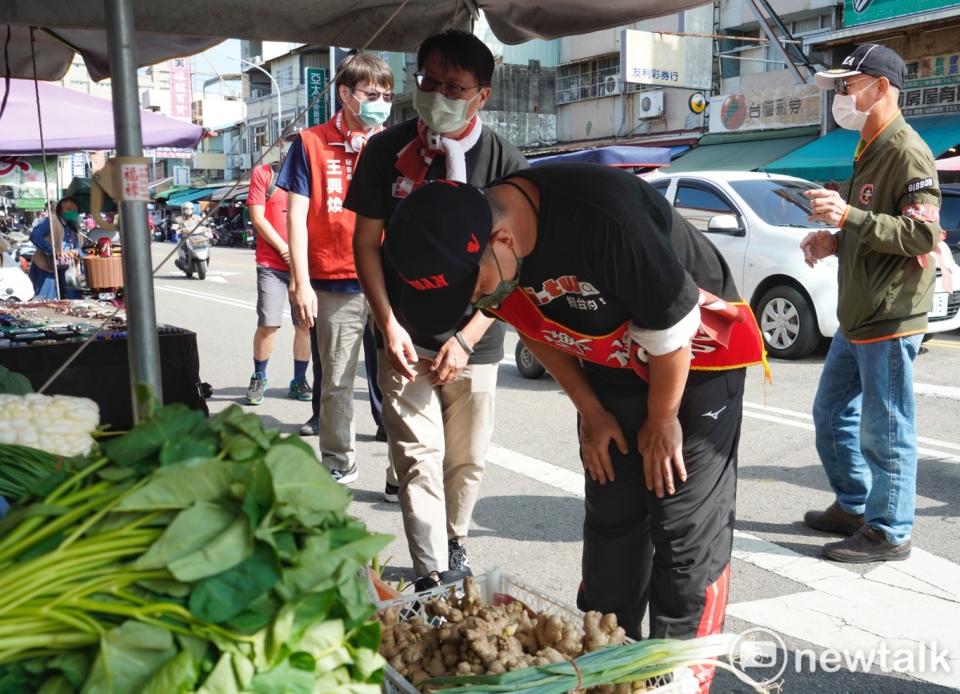 陳柏惟向大肚市場的一位攤商鞠躬致意。   圖：張良一/攝