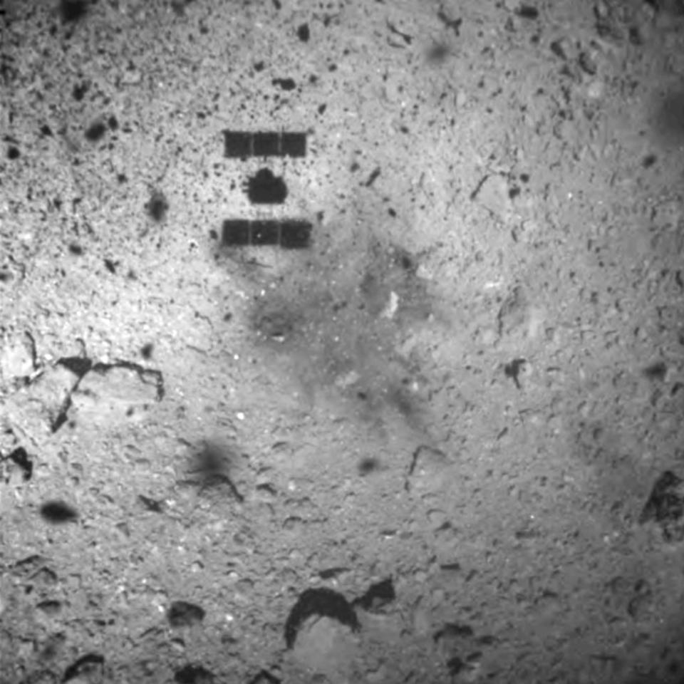 FILE - This Feb. 22, 2019, file image released by the Japan Aerospace Exploration Agency (JAXA) shows the shadow, center above, of the Hayabusa2 spacecraft after its successful touchdown on the asteroid Ryugu. Japan's space agency JAXA said Friday, April 5, 2019, its Hayabusa2 spacecraft released an explosive onto an asteroid to make a crater on its surface and collect underground samples to find possible clues to the origin of the solar system. The mission is the riskiest for Hayabusa2, as it has to immediately get away so it won't get hit by flying shards from the blast. (JAXA via AP, File)