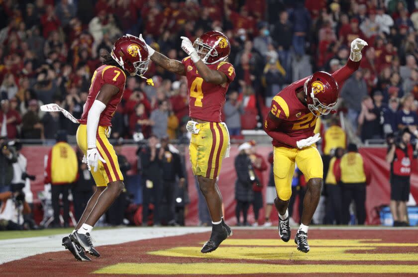 LOS ANGELES, CA - NOVEMBER 26, 2022: USC Trojans defensive back Calen Bullock (7) reacts with USC Trojans defensive back Max Williams (4) and USC Trojans defensive back Latrell McCutchin (21) after intercepting a pass late in the game against Notre Dame at the Coliseum on November 26, 2022 in Los Angeles, California.(Gina Ferazzi / Los Angeles Times)