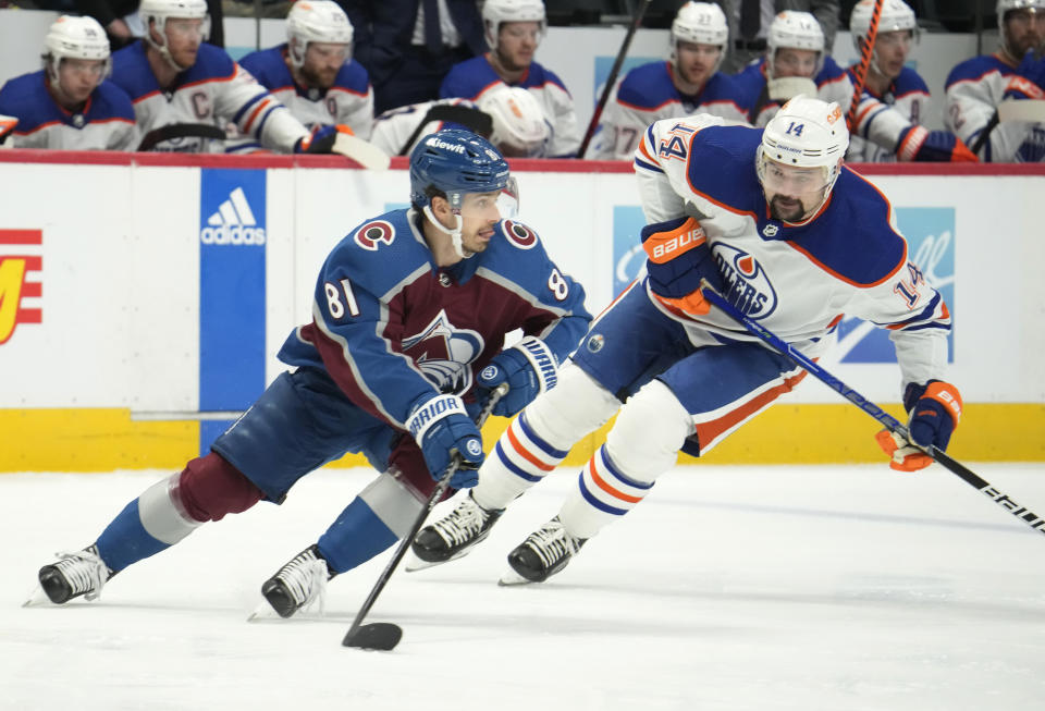 Colorado Avalanche center Denis Malgin, left, picks up the puck as Edmonton Oilers center Devin Shore, right, pursues in the second period of an NHL hockey game Sunday, Feb. 19, 2023, in Denver. (AP Photo/David Zalubowski)