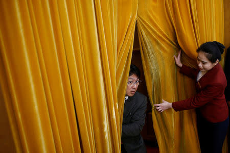 An usher lifts curtains for a man arriving to the Great Hall of the People during the opening session. REUTERS/Thomas Peter