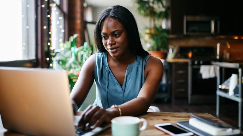 Young woman sitting in her Downtown Los Angeles apartment, finishing work in the evening while having another cup of coffee.