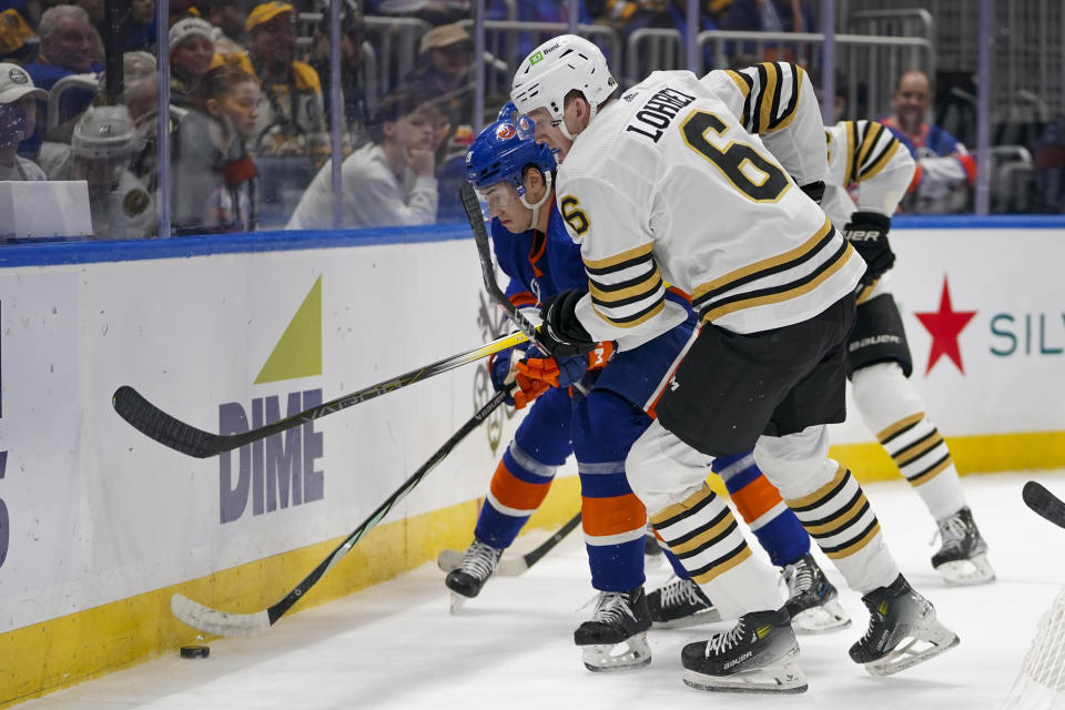 New York Islanders defenseman Alexander Romanov (28) and Boston Bruins defenseman Mason Lohrei (6) vie for the puck during the first period of an NHL hockey game in Elmont, N.Y., Friday, Dec. 15, 2023. (AP Photo/Peter K. Afriyie)