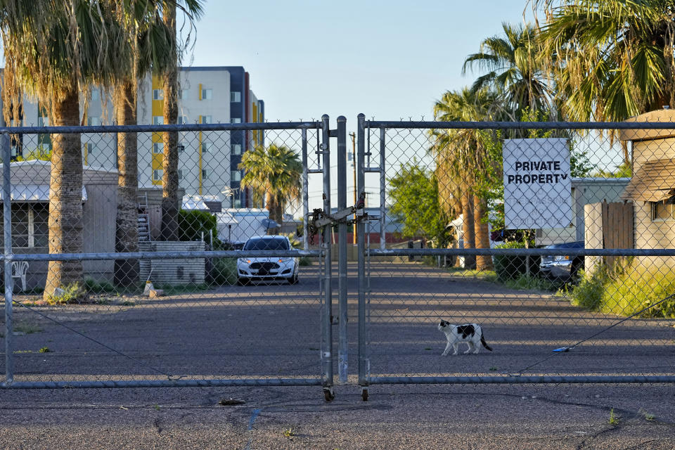 The second of three entrances to the Periwinkle Mobile Home Park is fenced off from the street, Thursday, April 11, 2023, in Phoenix. Remaining residents of the park are facing an eviction deadline of May 28 due to a private university's plan to redevelop the land for student housing. (AP Photo/Matt York)