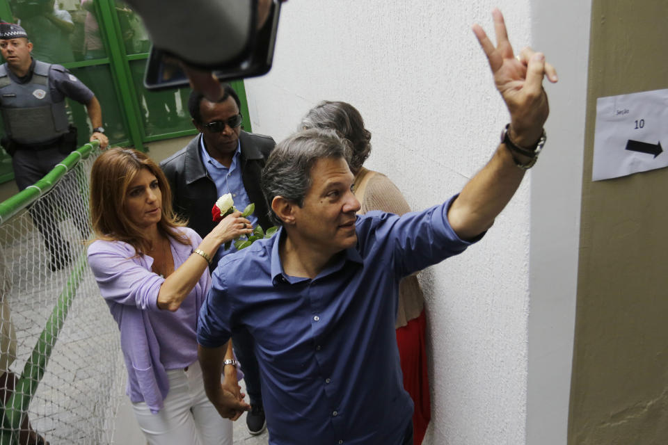 Workers' Party presidential candidate Fernando Haddad, accompanied by his wife Ana Estela, makes a victory sign as he arrives at a polling station to cast his vote in the presidential runoff election in Sao Paulo, Brazil, Sunday, Oct. 28, 2018. Haddad is facing the far-right congressman Jair Bolsonaro. (AP Photo/Nelson Antoine)