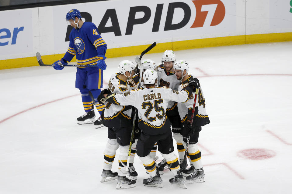 Boston Bruins right wing David Pastrnak is congratulated by teammates after scoring during the first period of an NHL hockey game as Buffalo Sabres defenseman Ilya Lyubushkin (46) skates by, Saturday, Dec. 31, 2022, in Boston. (AP Photo/Mary Schwalm)