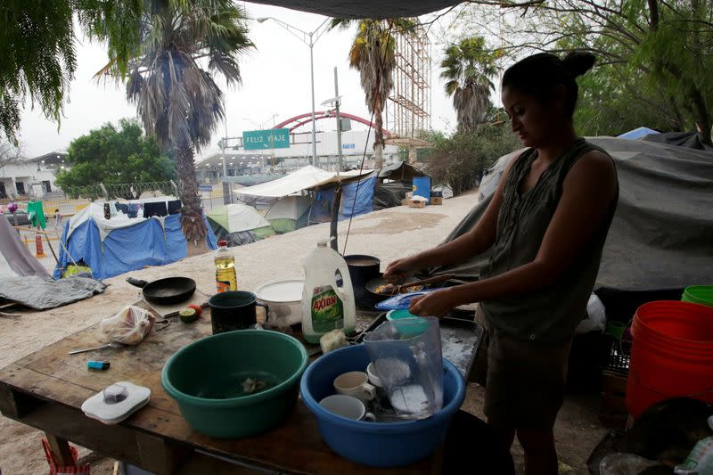 A Central American migrant washes dishes at an encampment of more than 2,000 migrants seeking asylum in the U.S., as local authorities prepare to respond to the coronavirus disease (COVID-19) outbreak, in Matamoros