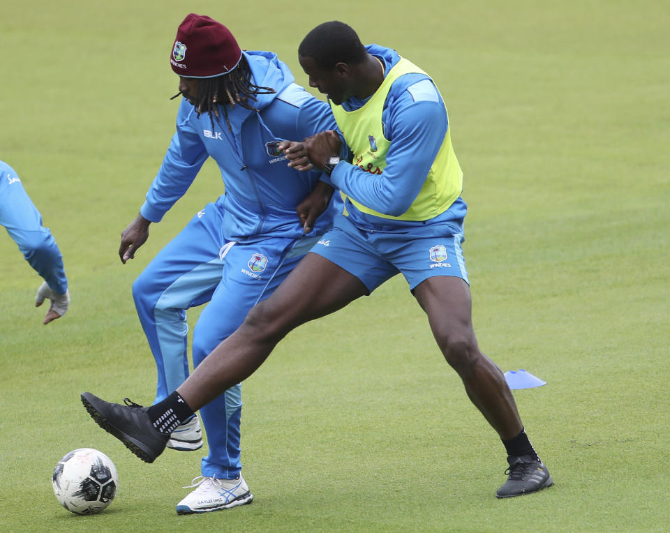 West Indies' Chris Gayle, left, and Carlos Brathwaite vie for the ball during a friendly game of soccer at a training session ahead of their Cricket World Cup match against India at Old Trafford in Manchester, England, Wednesday, June 26, 2019. (AP Photo/Aijaz Rahi)