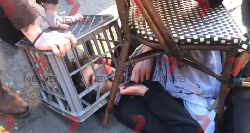Screengrab taken with permission from a video issued by 7 News of a man being tackled with a milk crate and chairs by members of the public in Sydney, Australia, following a knife attack.