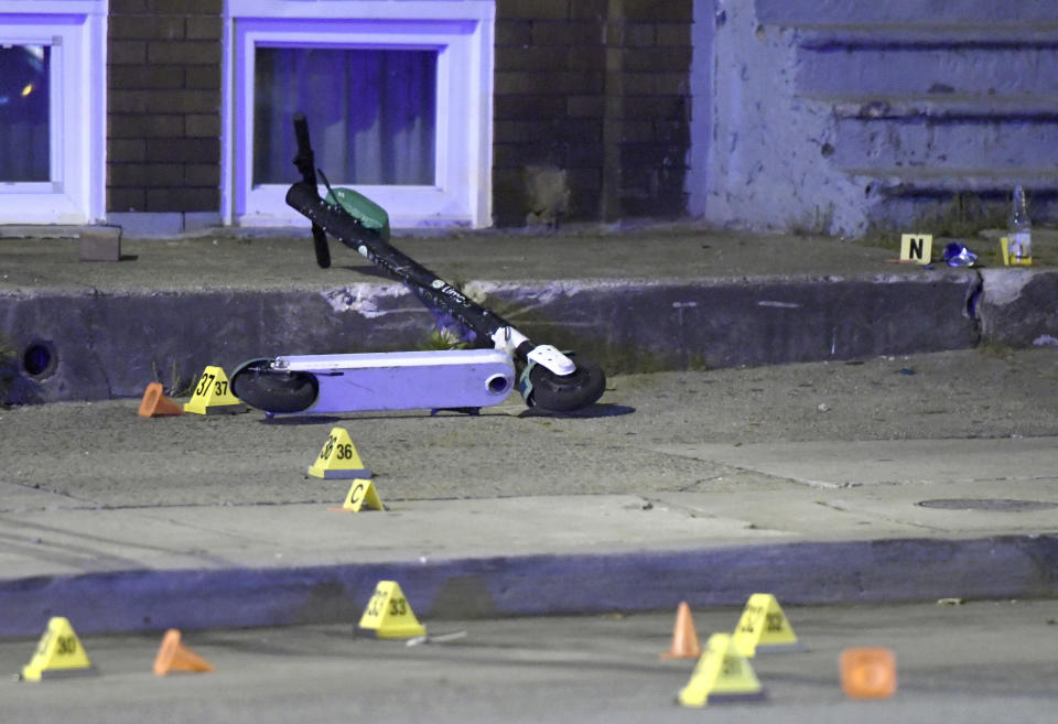 A scooter lies among evidence markers near the scene where authorities say seven people were shot, at least one fatally, Sunday, April 28, 2019, in Baltimore. (AP Photo/Steve Ruark)