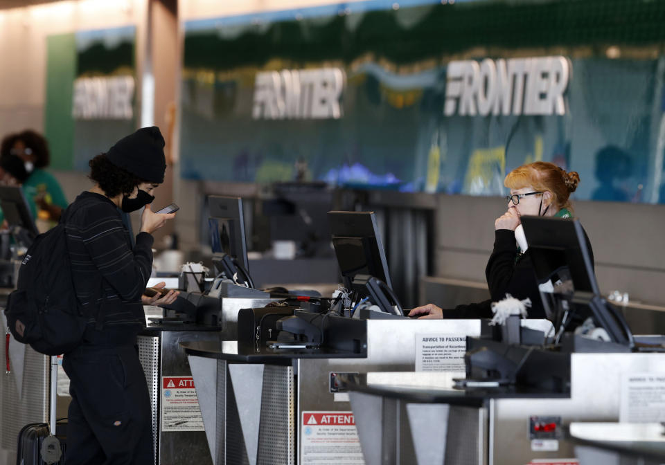 A passenger, left, checks in with an agent at the ticketing counter for Frontier Airlines at Denver International Airport, Sunday, May 3, 2020, in Denver during the coronavirus outbreak. (AP Photo/David Zalubowski)