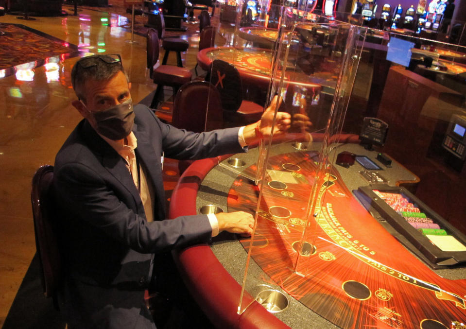 Ron Baumann, a regional president with Caesars Entertainment, sits Wednesday, July 1, 2020, at a card table at Harrah's casino in Atlantic City, N.J., where plexiglass barriers have been installed to separate gamblers to prevent the spread of the coronavirus. Five of Atlantic City's casinos will reopen on Thursday, while three others, including Harrah's, will open Friday. (AP Photo/Wayne Parry)