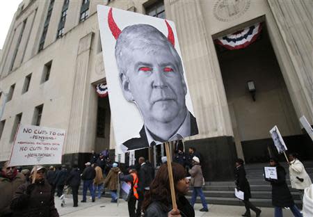 A protester holds a poster depicting Michigan Governor Rick Snyder as a devil, during a protest against cuts in city workers' pensions and the filing of the Municipal Bankruptcy, in front of the Federal Court House in Detroit, Michigan October 28, 2013. REUTERS/Rebecca Cook