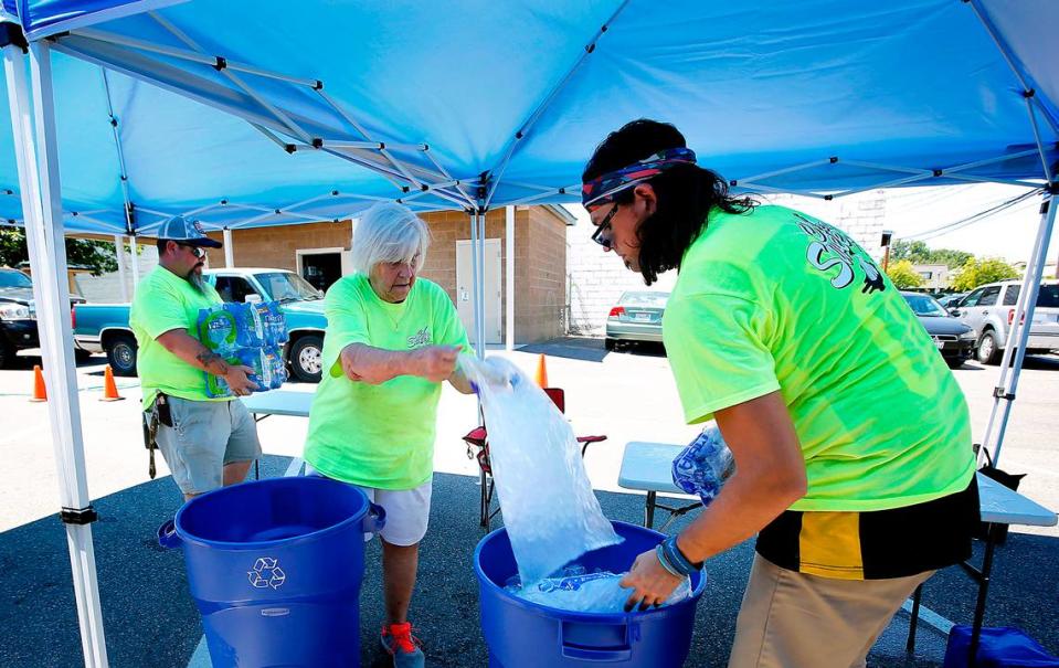 Clean Sweep Tri-Cities volunteers Matt McKee, Lynne Mckee and Brian Bartlett, from left, add ice and bottled water to barrels in June 2021 at the shade station set up in downtown Kennewick. Tri-City Herald file