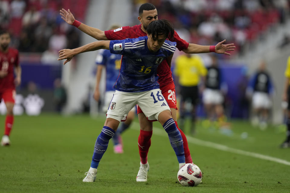 Japan's Seiya Maikuma is challenged by Bahrain's Mahdi Humaidan, rear, during the Asian Cup Round of 16 soccer match between Bahrain and Japan, at Al Thumama Stadium in Doha, Qatar, Wednesday, Jan. 31, 2024. (AP Photo/Thanassis Stavrakis)