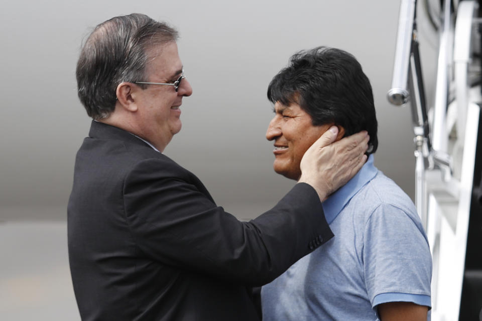 Mexican Foreign Minister Marcelo Ebrard, left, welcomes former Bolivian President Evo Morales upon his arrival to Mexico City, Tuesday, Nov. 12, 2019. Mexico granted asylum to Morales, who resigned on Nov. 10 under mounting pressure from the military and the public after his re-election victory triggered weeks of fraud allegations and deadly protests. (AP Photo/Eduardo Verdugo)