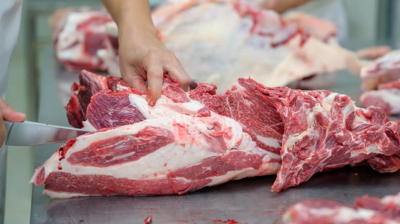 Person trimming beef with knife