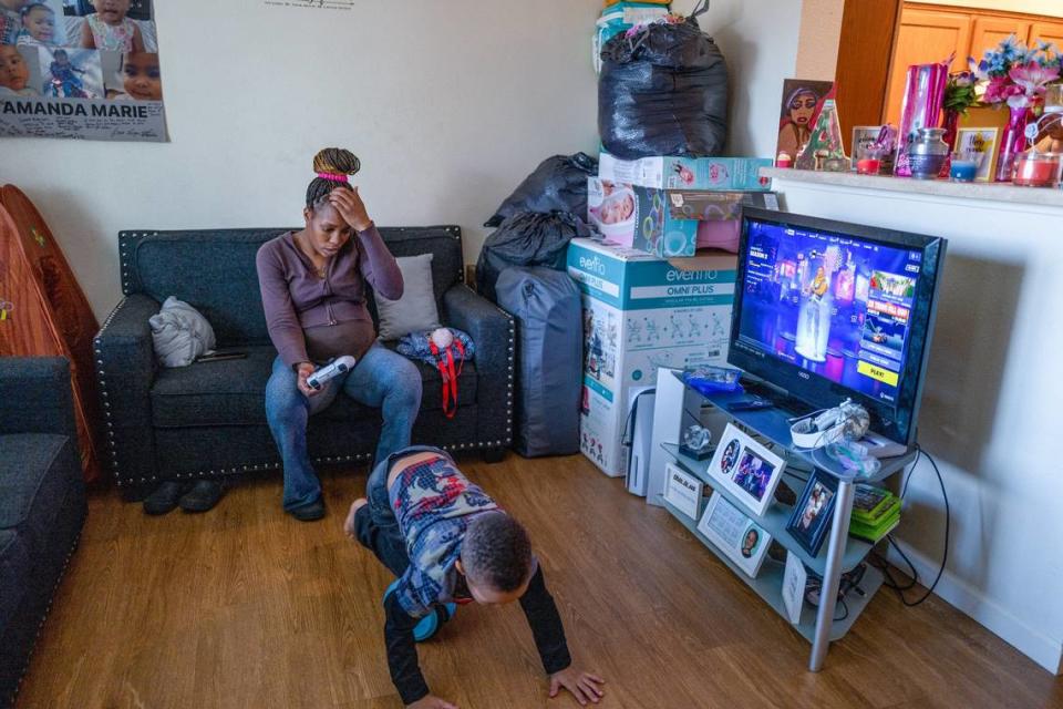 Elijah plays while his mother Marquisha Brown watches him in their Yolo County apartment last month. The living room is filled with memories of her daughter Amanda, including an urn with some of her ashes that rests on the counter near other memorial items and the poster at left, and supplies for the baby girl Brown is expecting in July with her fiance.