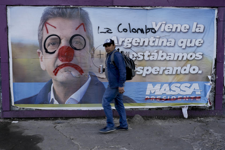 Un hombre camina al lado de una pancarta pintarrajeada del ministro de Economía Sergio Massa, candidato presidencial oficialista, en Buenos Aires, Argentina, el sábado 18 de noviembre de 2023. Massa se enfrentará a Javier Milei, candidato de la alianza Libertad Avanza. (AP Foto/Rodrigo Abd)