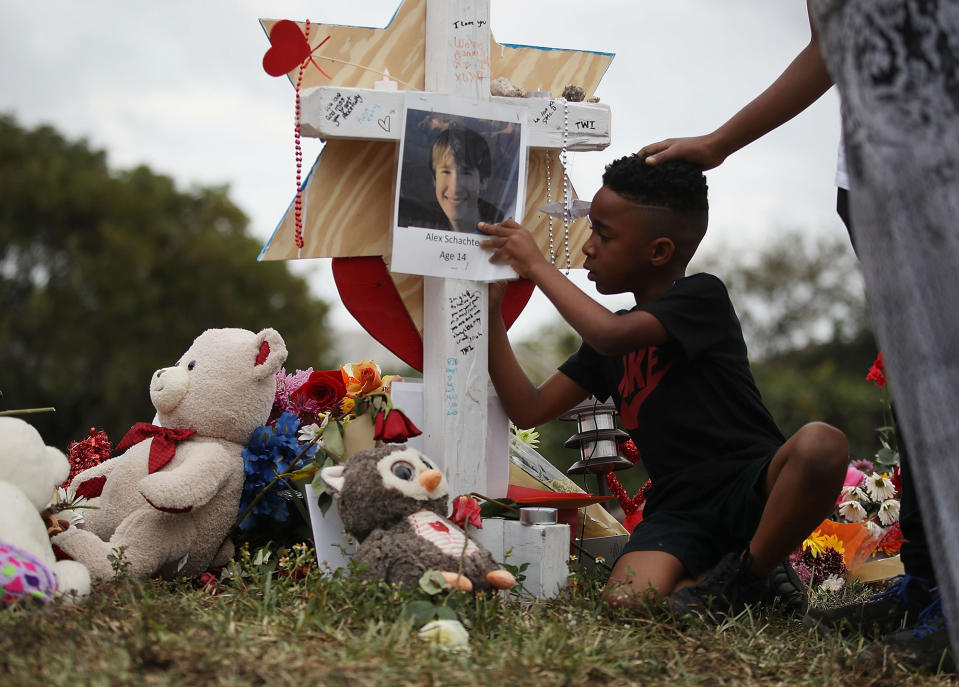 <p>Nekhi Charlemagne writes a message on a cross setup in a makeshift memorial in front of Marjory Stoneman Douglas High School on February 19, 2018 in Parkland, Florida. (Photo: Joe Raedle/Getty Images) </p>