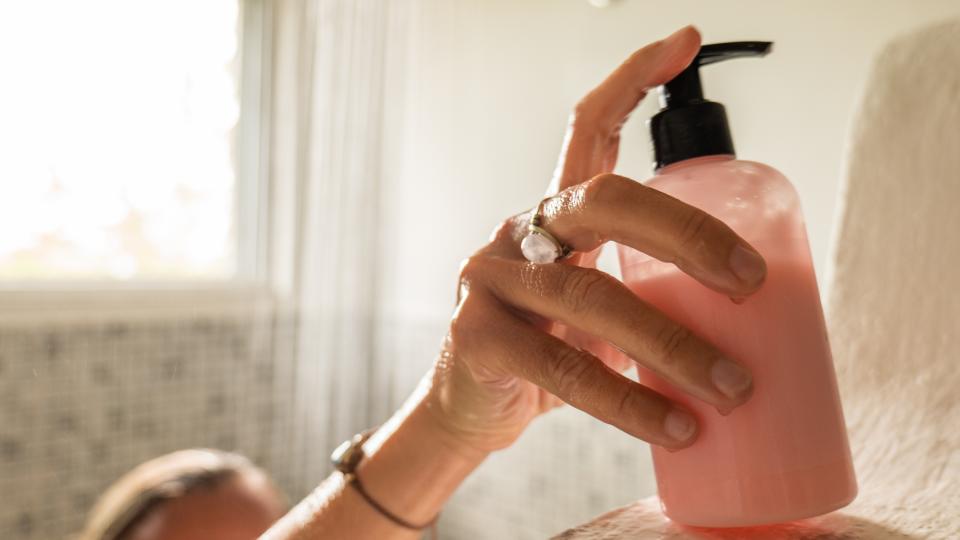 A woman is seen picking up a bottle of pink conditioner whilst in the shower