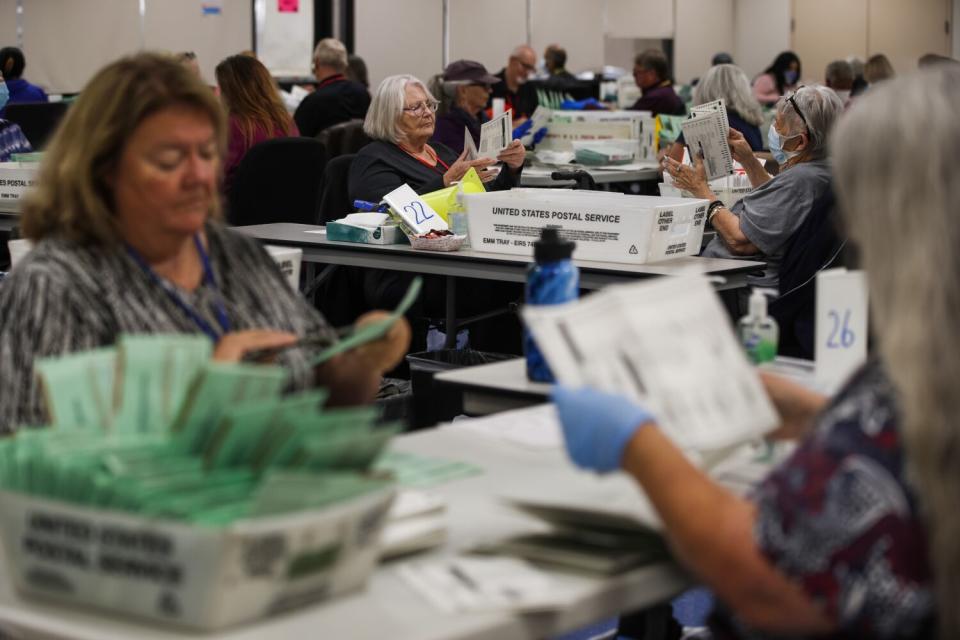 Election workers look over ballots.