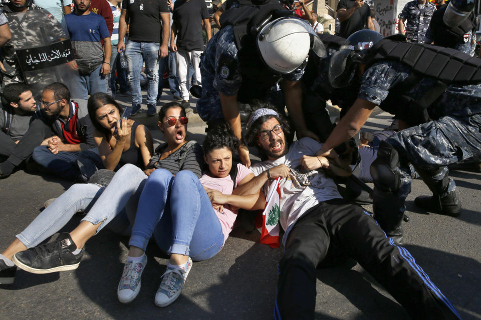 Anti-government protesters lie on a road, as they scream and hold each others while riot police try to remove them and open the road, in Beirut, Lebanon, Thursday, Oct. 31, 2019. Army units and riot police took down barriers and tents set up in the middle of highways and major intersections Thursday. (AP Photo/Bilal Hussein)