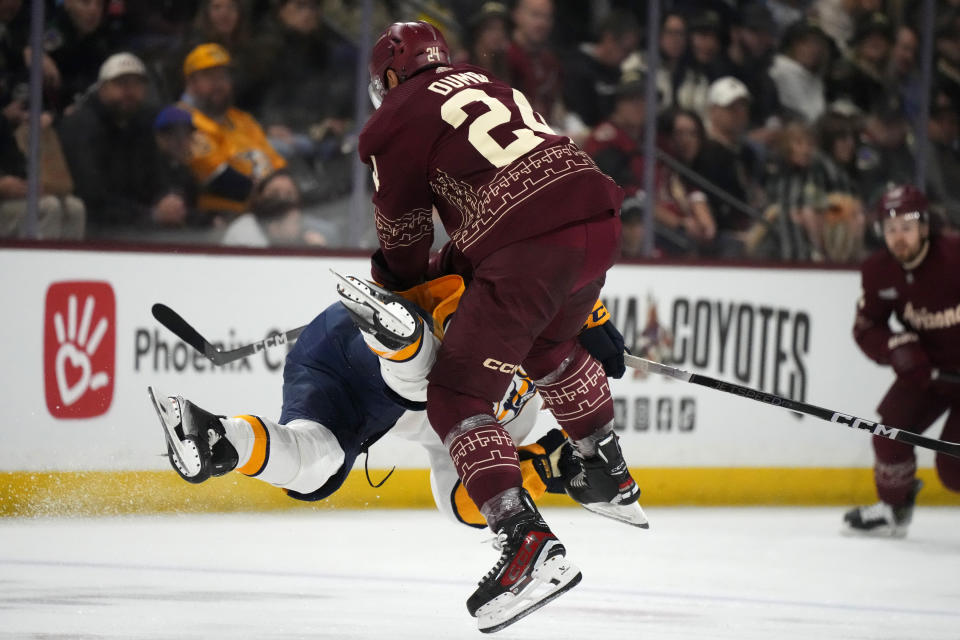 Arizona Coyotes defenseman Matt Dumba (24) checks Nashville Predators center Tommy Novak to the ice during the second period of an NHL hockey game Saturday, Jan. 20, 2024, in Tempe, Ariz. (AP Photo/Ross D. Franklin)