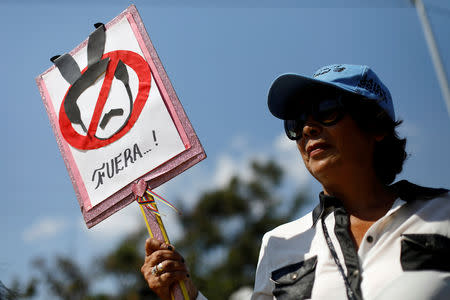 An opposition supporter holds a sign that reads "Out" as she gathers to rally against Venezuelan President Nicolas Maduro's government at the Colombian-Venezuelan border over the Simon Bolivar international bridge, on the outskirts of Cucuta, Colombia February 15, 2019. REUTERS/Edgard Garrido