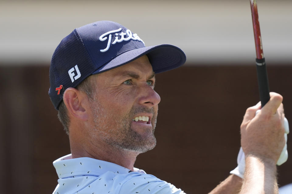 Webb Simpson wears a red pin on his hat as he watches his tee shot on the 17th hole during the final round of the Charles Schwab Challenge golf tournament at Colonial Country Club in Fort Worth, Texas, Sunday, May 26, 2024. (AP Photo/LM Otero)