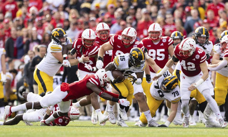 Iowa's Tyler Goodson (15) carries the ball as Nebraska's Marquel Dismuke (9) dives for the tackle during the first half of an NCAA college football game, Friday, Nov. 26, 2021, at Memorial Stadium in Lincoln, Neb. (AP Photo/Rebecca S. Gratz)