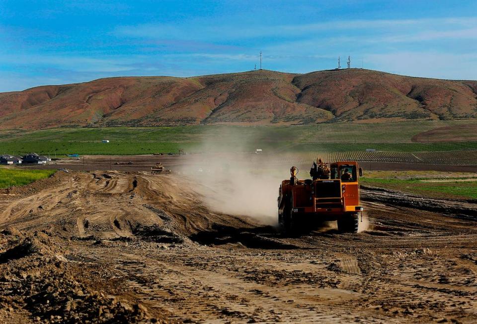 A piece of heavy earth moving equipment rumbles through the dirt creating the foundation of a new road for a new housing development called South Orchard in the Badger Mountain South area of Richland.