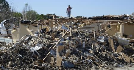 Resident Jerryco Green climbs over a collapse structure as he looks for items in Tupelo, Mississippi after a tornado hit the town April 30, 2014. REUTERS/Gene Blevins